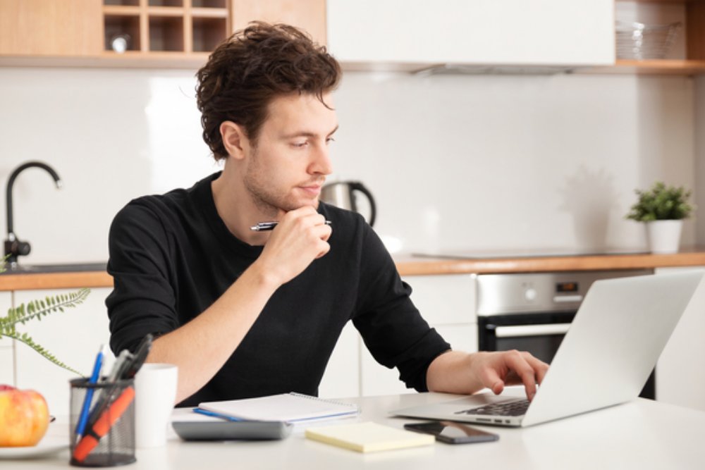 Man working in his kitchen on a laptop.